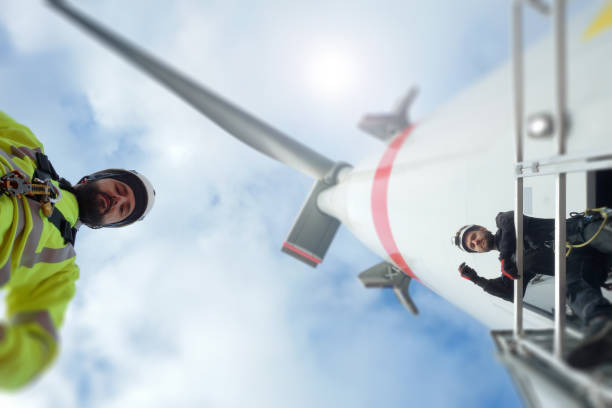 istock Offshore manual worker standing under gigantic wind-turbine 1138444663