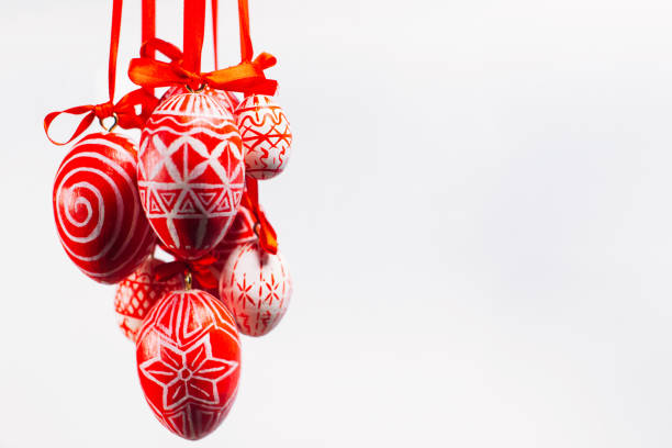 istock Bundle of Easter eggs with folk Ukrainian pattern hang on red ribbons from left side on white background. 1138447489