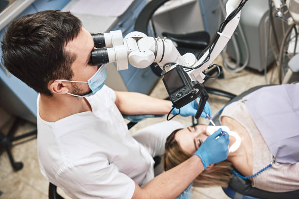 istock Personalized & comfortable. Male dentist look at the patient using professional dental binocular microscope. Modern dental clinic. High angle 1138448412