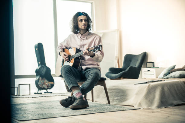 istock Pleasant dark-haired young musician practicing in guitar mastery 1138449233