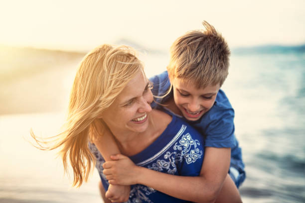istock Mother giving son piggyback ride on beach 1138450813