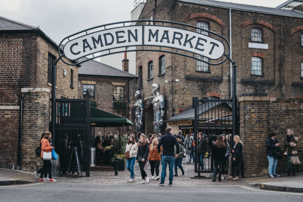 People entering Camden Market, London, UK, through the gates, under a name sign. stock photo