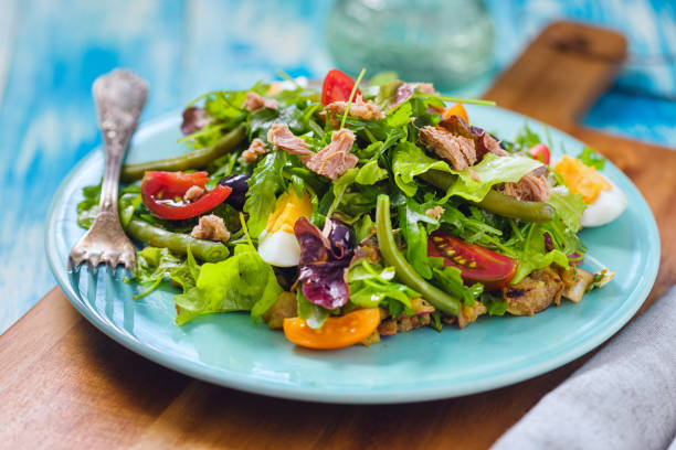Fresh Nicoise Salad Fresh Niçoise salad with tuna, new potato, eggs, green bean, cherry tomatoes, lettuces and black olives in a plate green bean vegetable bean green stock pictures, royalty-free photos & images