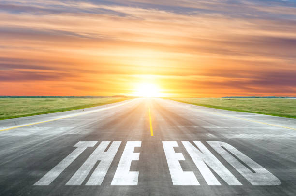 istock Asphalt road with text - The End. The highway goes into the sunset sky. 1138457035