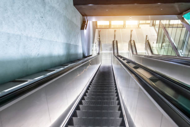 escalators long escalier descendant dans le métro, infrastructure de transport urbain. - escalator office vehicle interior built structure photos et images de collection