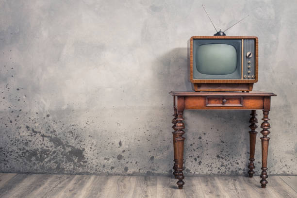 istock Retro old outdated TV receiver from circa 50s on wooden table front textured concrete wall background. Vintage style filtered photo 1138458211