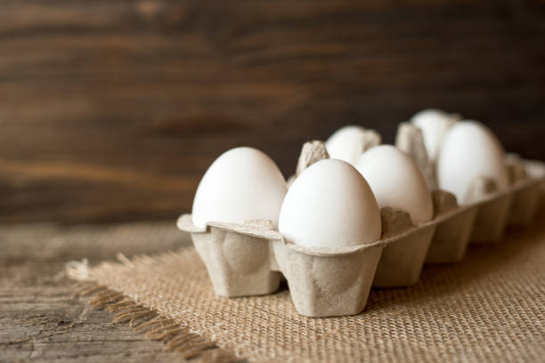 istock Raw eggs in egg box on wooden background. 1138463058