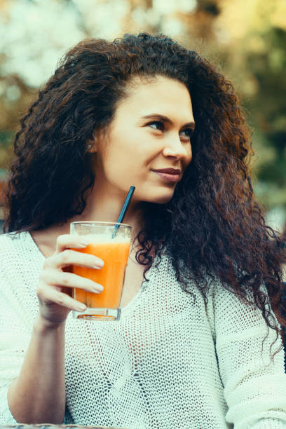 istock Beautiful young woman drinking orange juice 1138463505