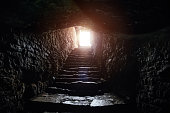 Underground passage under old medieval fortress. Old stone stairs to exit of tunnel