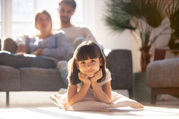 bella bambina sdraiata sul cuscino sul pavimento caldo - floor two parent family couple home interior foto e immagini stock