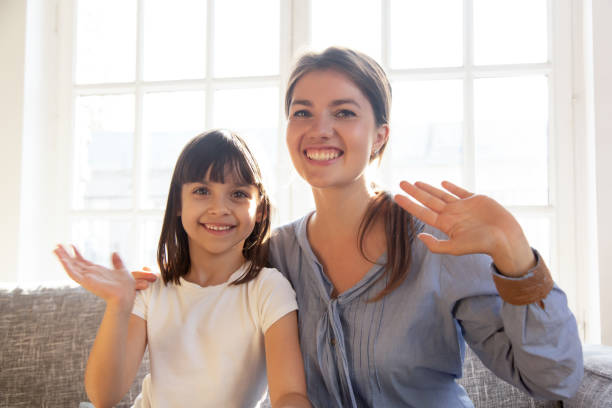 istock Happy mother and daughter looking at webcam and wave hands 1138470078