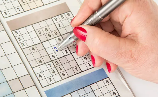 Woman's hand with a pen is filling out sudoku