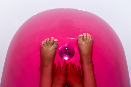 Children's feet in pink colored bath water