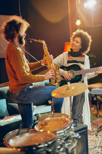 istock Mixed race woman playing acoustic guitar while man playing saxophone. 1138473811