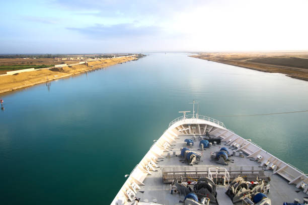Nave in transito attraverso il Canale di Suez. Sabbia del deserto su entrambi i lati. Prua e rotaia della nave. - foto stock