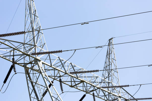 Closeup high voltage electricity pylon, blue sky background with copy space, full frame horizontal composition