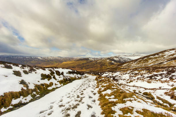 istock Snow foot traces in the mountain under a blue sky and white clouds 1138479627