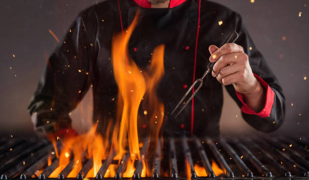 Closeup of chef holding fork above the grill. Concept of food preparation, ready for product placement.