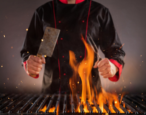 Closeup of chef holding fork above the grill. Concept of food preparation, ready for product placement.