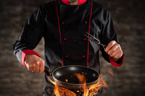 Closeup of chef holding frying pan above grill. Closeup of chef holding empty frying pan above grill. Concept of food preparation, ready for product placement. polytetrafluoroethylene photos stock pictures, royalty-free photos & images