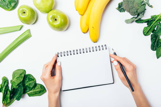 вид женщины руку письменной форме в пустой блокнот - leaf vegetable planning food healthy eating стоковые фото и изображения