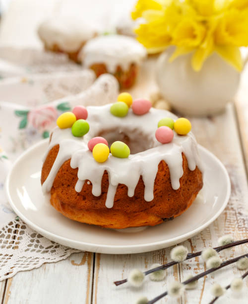 istock Easter yeast cake (Babka) covered with icing and decorated with marzipan eggs on a white plate on a wooden table. 1138490624