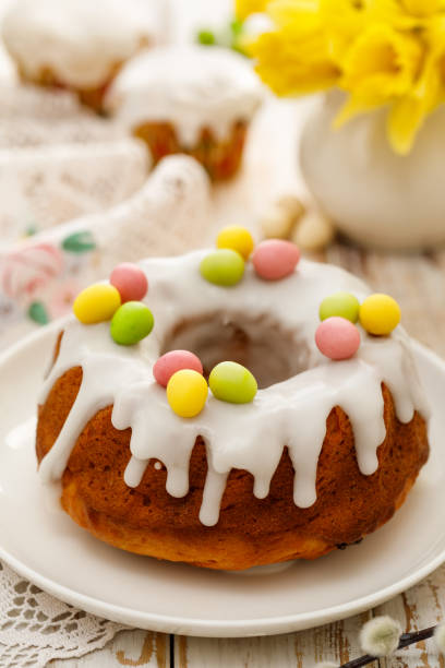 istock Easter yeast cake (Babka) covered with icing and decorated with marzipan eggs on a white plate on a wooden table. 1138490698