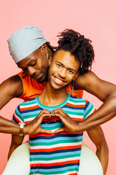 portrait of a laughing young couple with happy heart shaped on shirt with hands - homosexual beautiful sensuality love imagens e fotografias de stock