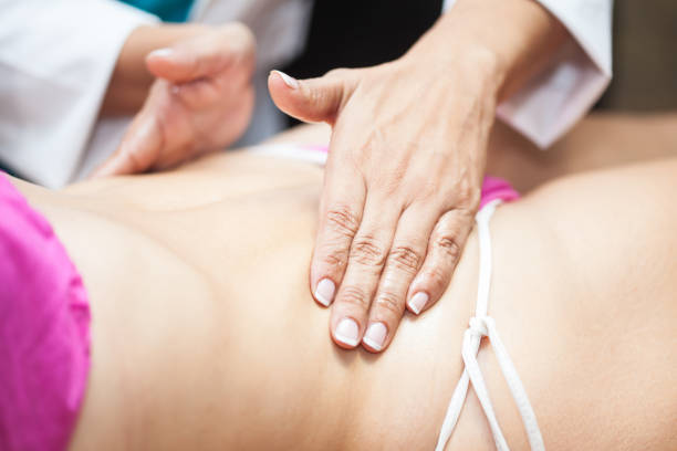 istock Doctor performing an abdominal massage on a young female patient 1138493530