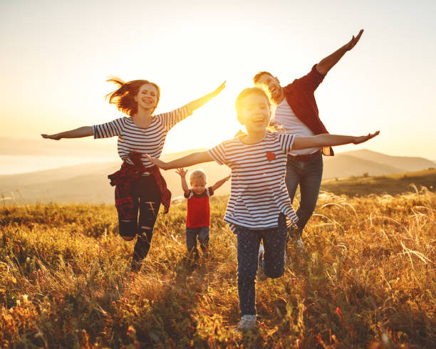 幸せな家族: 日没の母、父、子供の息子と娘 - child dancing ethnic outdoors ストックフォトと画像