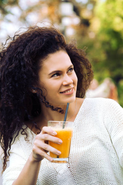 istock Beautiful young woman drinking orange juice 1138495490
