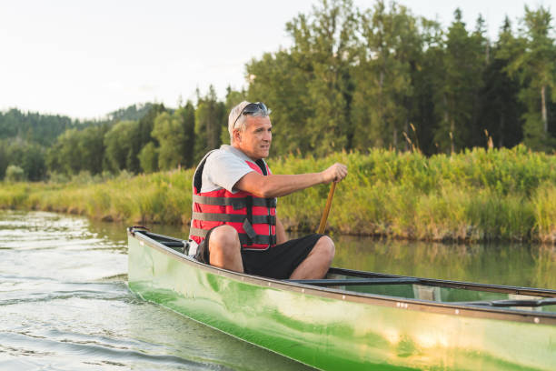 istock Senior couple canoeing together around a forested lake. 1138505021