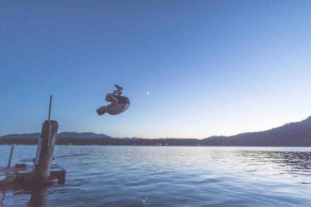 istock Young man dives into a lake off pier at dusk 1138505027