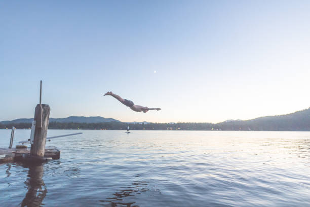 istock Young man dives into a lake off pier at dusk 1138505029