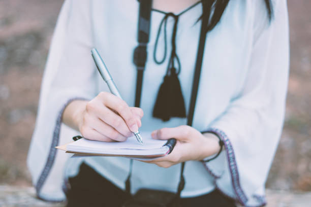 istock young girl writing into her diary about recipient address on mailing envelope,female hands sending letter,student writes information portable net-book while prepare for lectures in University campus 1138520490