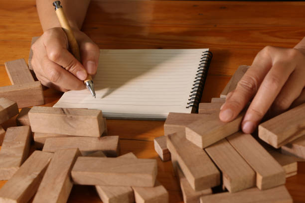 istock woman hand writing on notebook with wooden blocks 1138523220