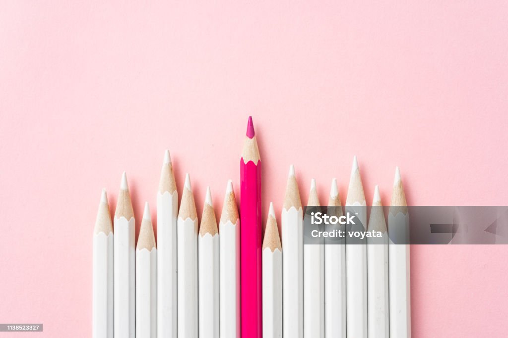 color pencil with leadership, teamwork concept Business and design concept - lot of white pencils and one color pencil on pink paper background. It's symbol of leadership, teamwork, success and unique. Standing Out From The Crowd Stock Photo