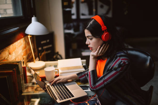 joven millennial usando el ordenador portátil mientras escucha música en su apartamento en el centro de los ángeles - home interior apartment working office fotografías e imágenes de stock