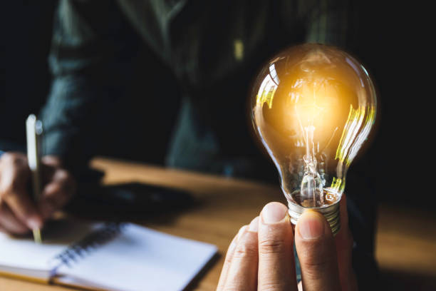 istock Business man holding light bulb on the desk in office and using  computer in  financial,accounting,energy,idea concept 1138532705