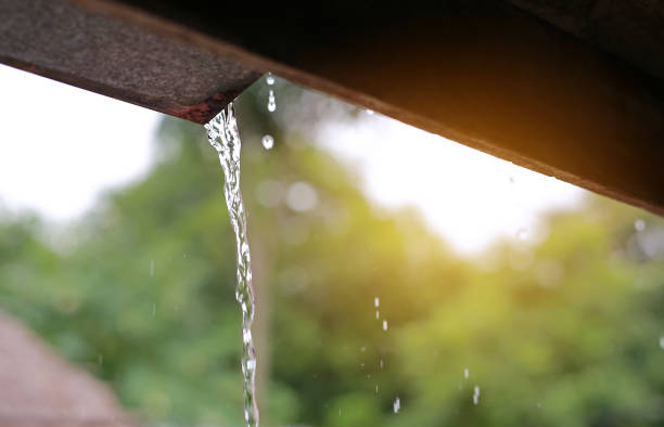 istock Rain pouring off roof with rays of sunlight. 1138542127