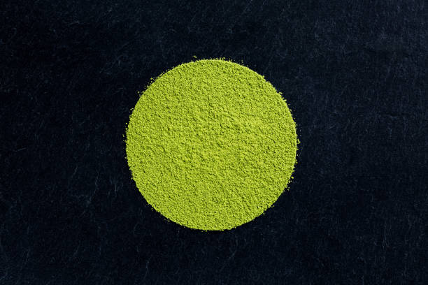 matcha green tea powder on black slate background Circular heap of matcha green tea powder on black slate background, view from above green tea powder stock pictures, royalty-free photos & images