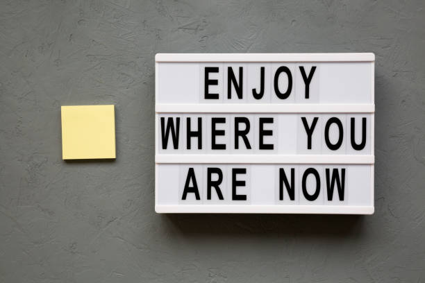 istock 'Enjoy where you are now' words on lightbox over gray background, top view. Flat lay, from above. 1138551012
