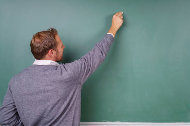 istock Male teacher writing on a blank chalkboard 1138552486