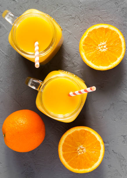 istock Fresh orange juice in glass jars over concrete surface, overhead view. From above, top view. Close-up. 1138553939