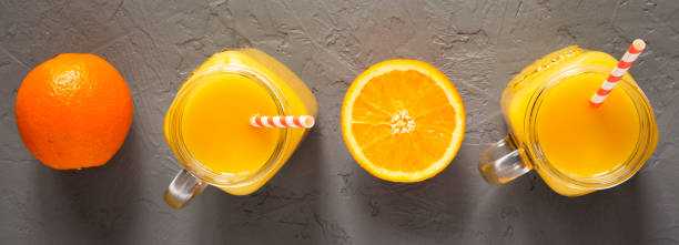 istock Orange juice in glass jars over gray surface, top view. 1138554045