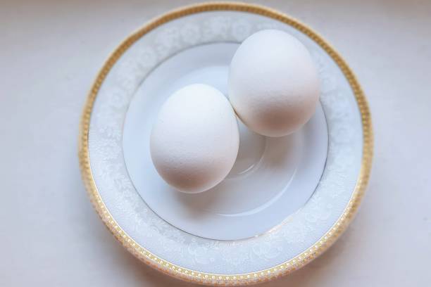 istock Two white eggs on a saucer with a gold frame. 1138555499