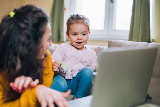 istock Mother and daughter using laptop on sofa 1138556355