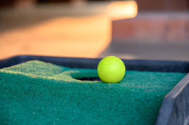 istock Green golf ball on edge hole cup on lawn putt 1138556719