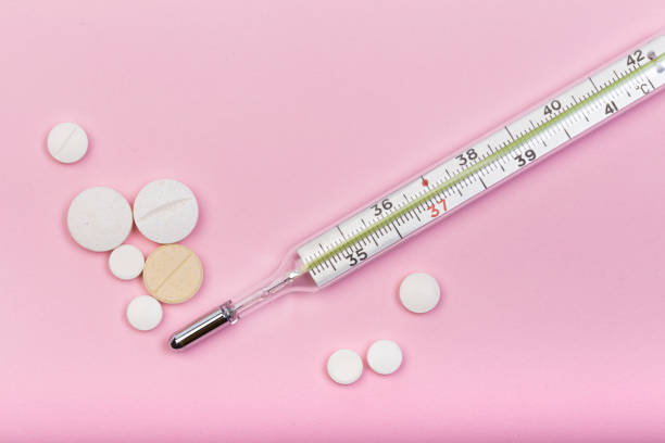 istock medical  thermometer and white pills on pink  background close up view- Image 1138556855