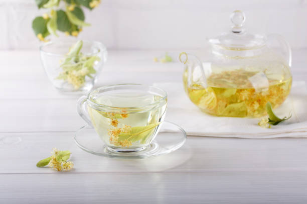 istock Linden tea in a transparent tea pot.  Glass cup and tea pot with herbal lime tree tea on white background. Medicinal plant, flowers used for herbal teas and tinctures. 1138559963